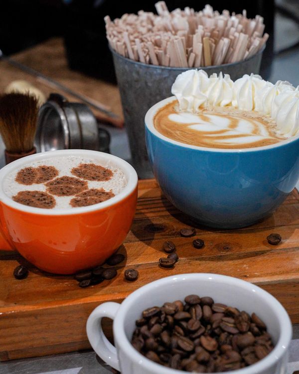 Cafés con arte latte y granos de café sobre la barra