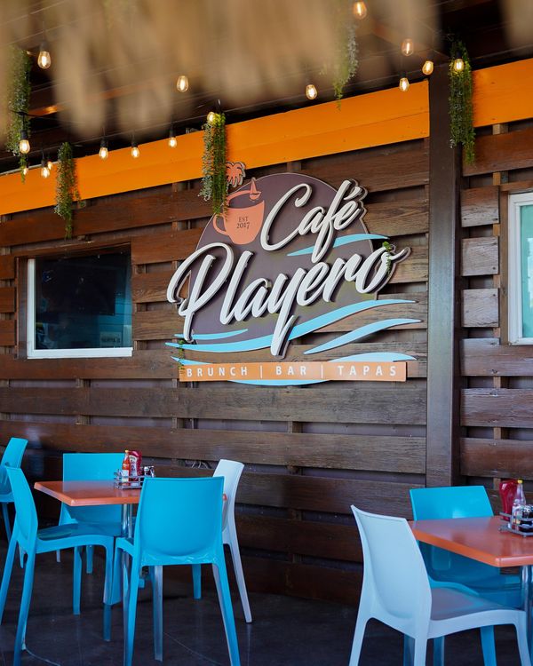 El salón de Café Playero de día, con el letrero y las sillas azules