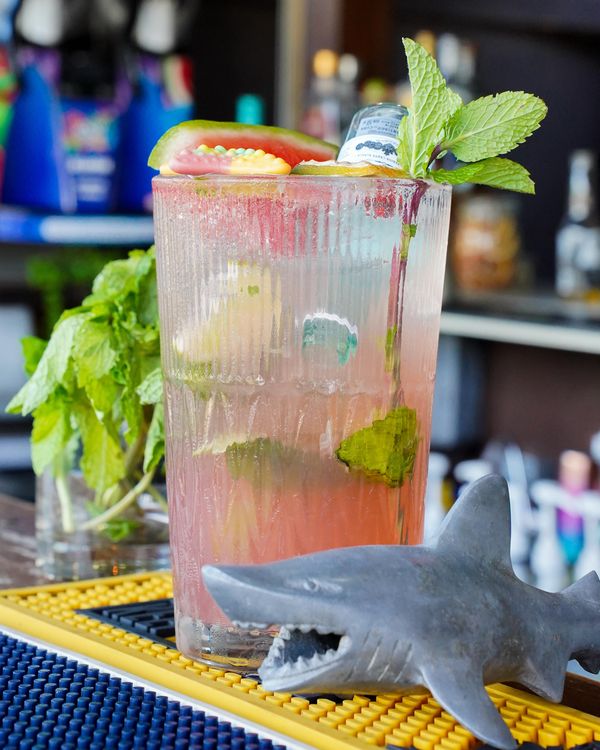 Un mojito de sandía con menta junto a un tiburón de juguete